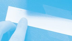 Photo en bichromie bleu et blanc, doigt lisant une étiquette braille